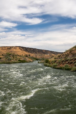 River running through lush green valley with waterfalls and cliffs