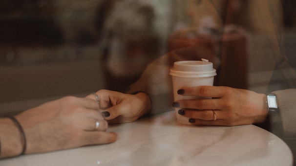 Two people sitting at a table with a cup of coffee