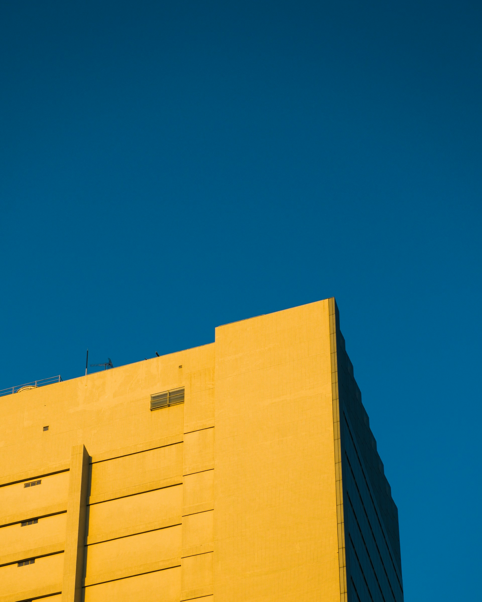 A tall yellow building with a blue sky in the background