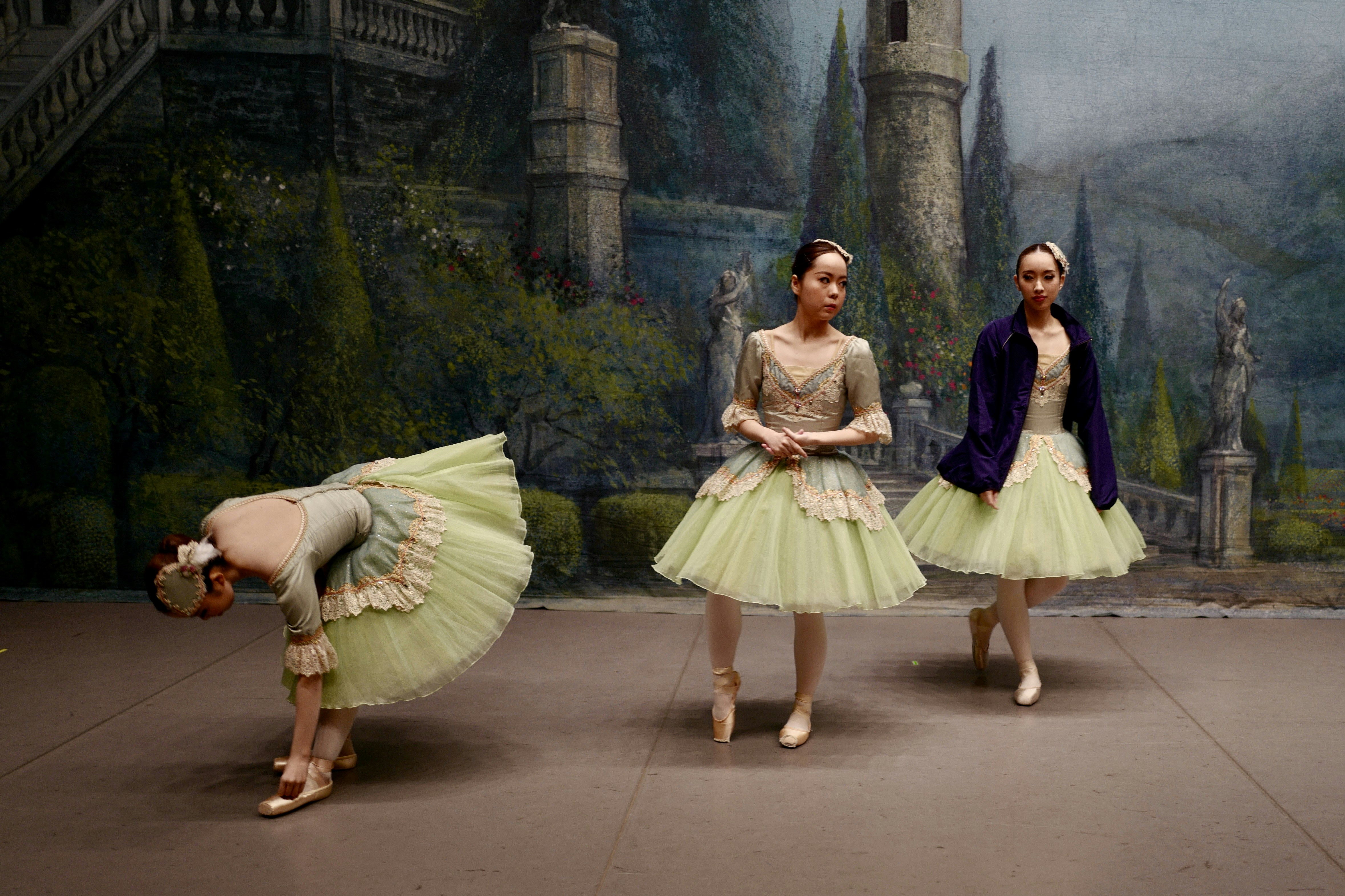 A group of ballerinas standing in front of a painting