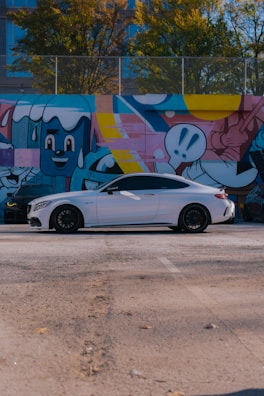 A white car parked in front of a colorful wall