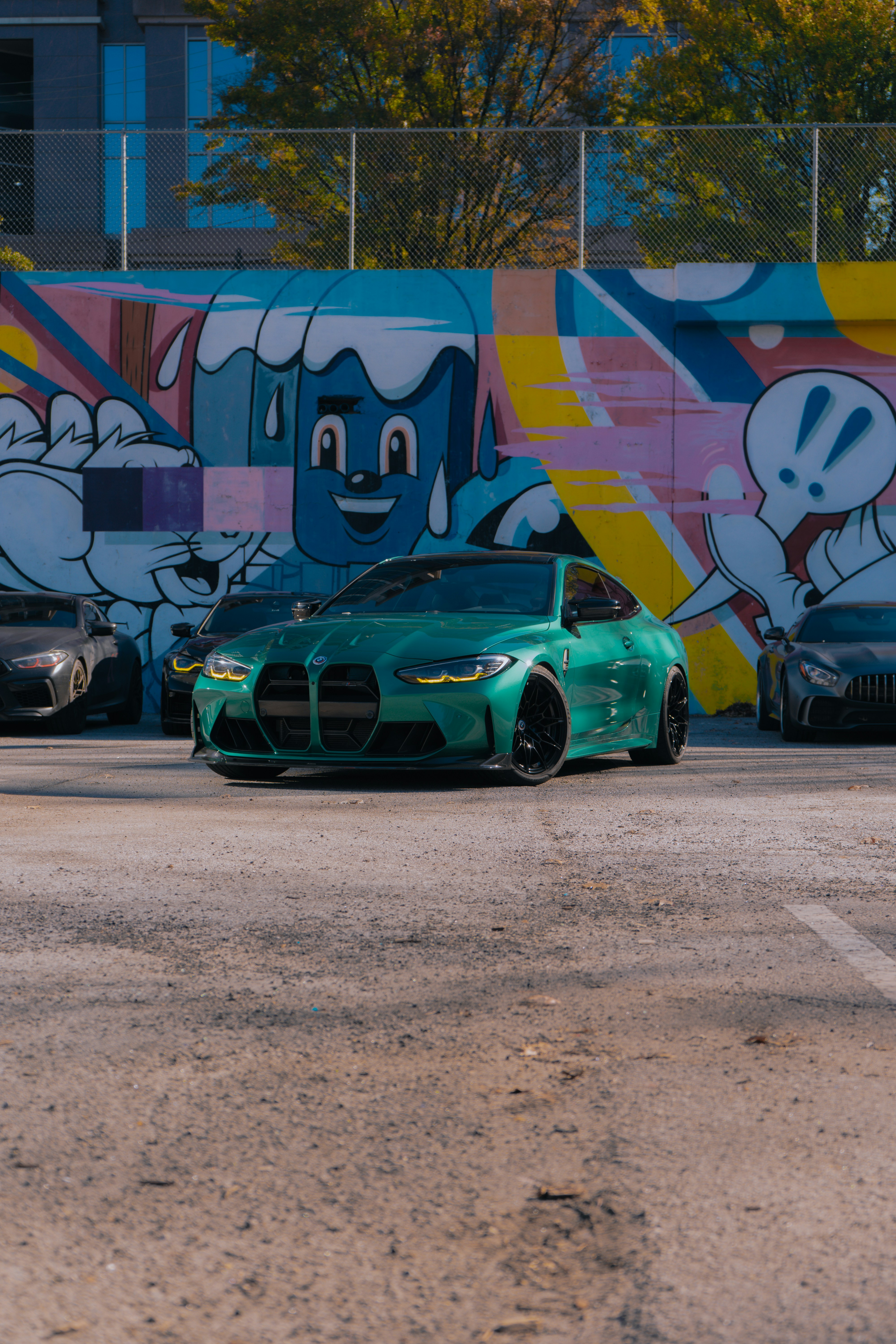 A green sports car parked in front of a colorful wall