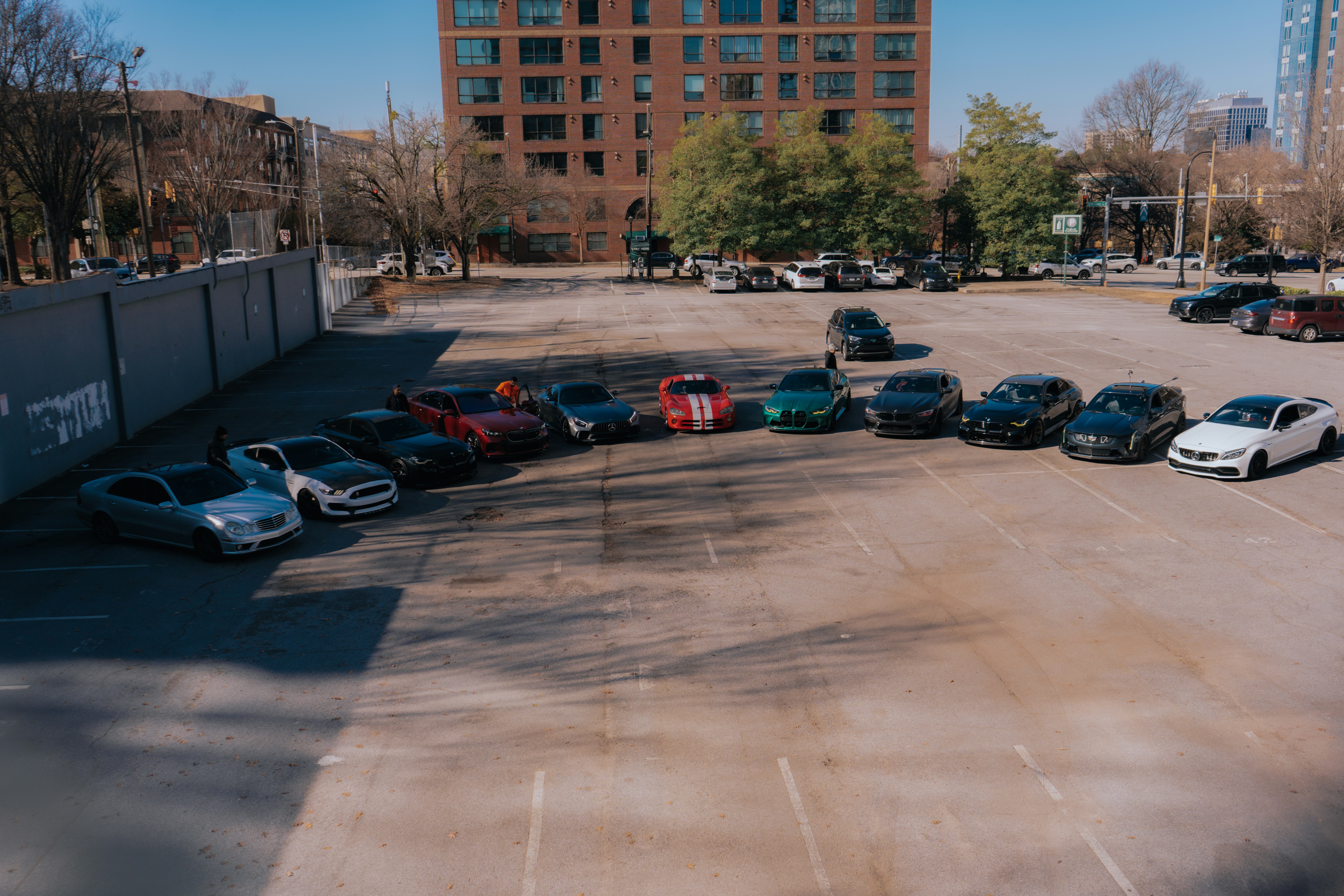 Row of used electric and gas cars parked on a dealer lot at sunset