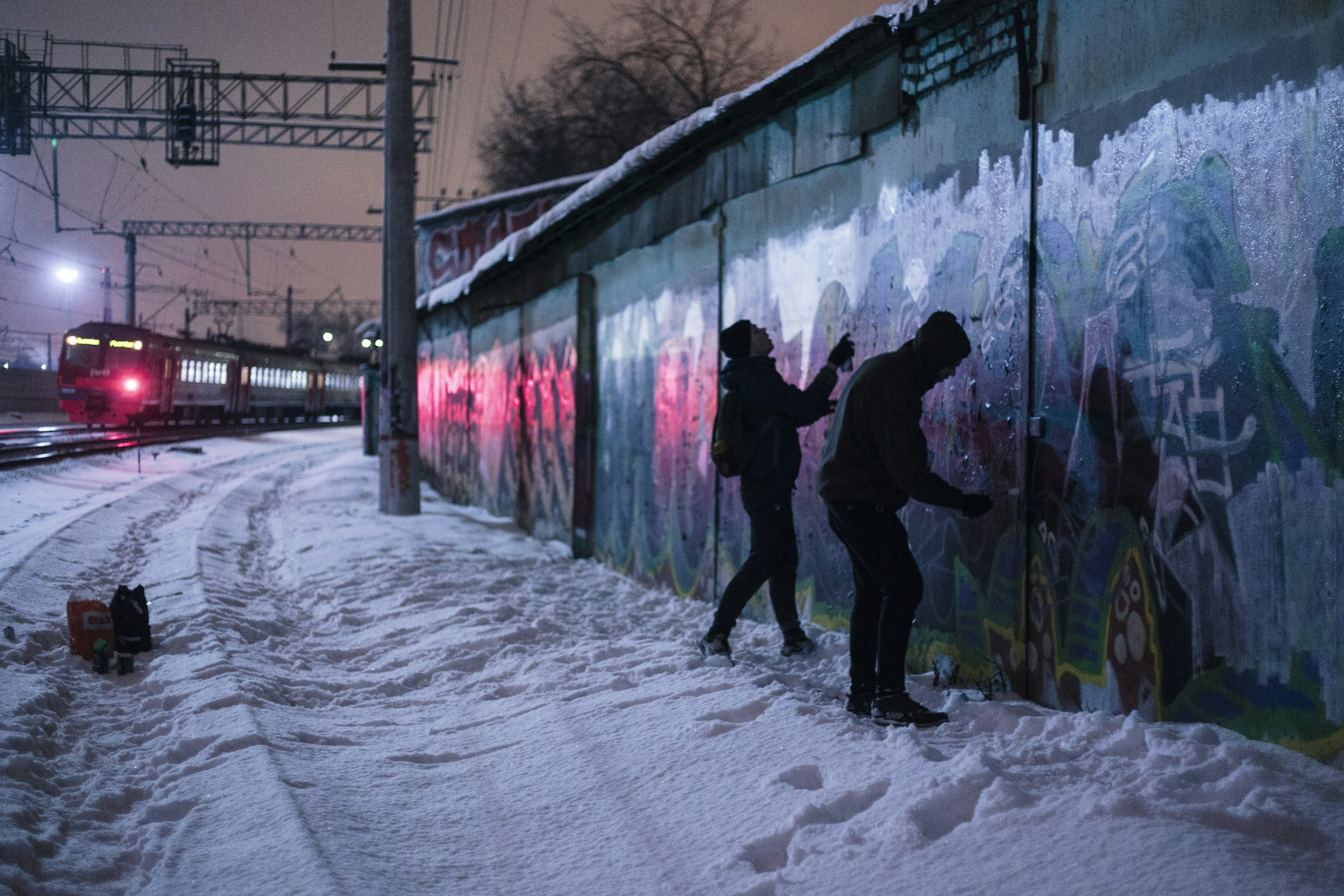 A couple of people standing next to a wall