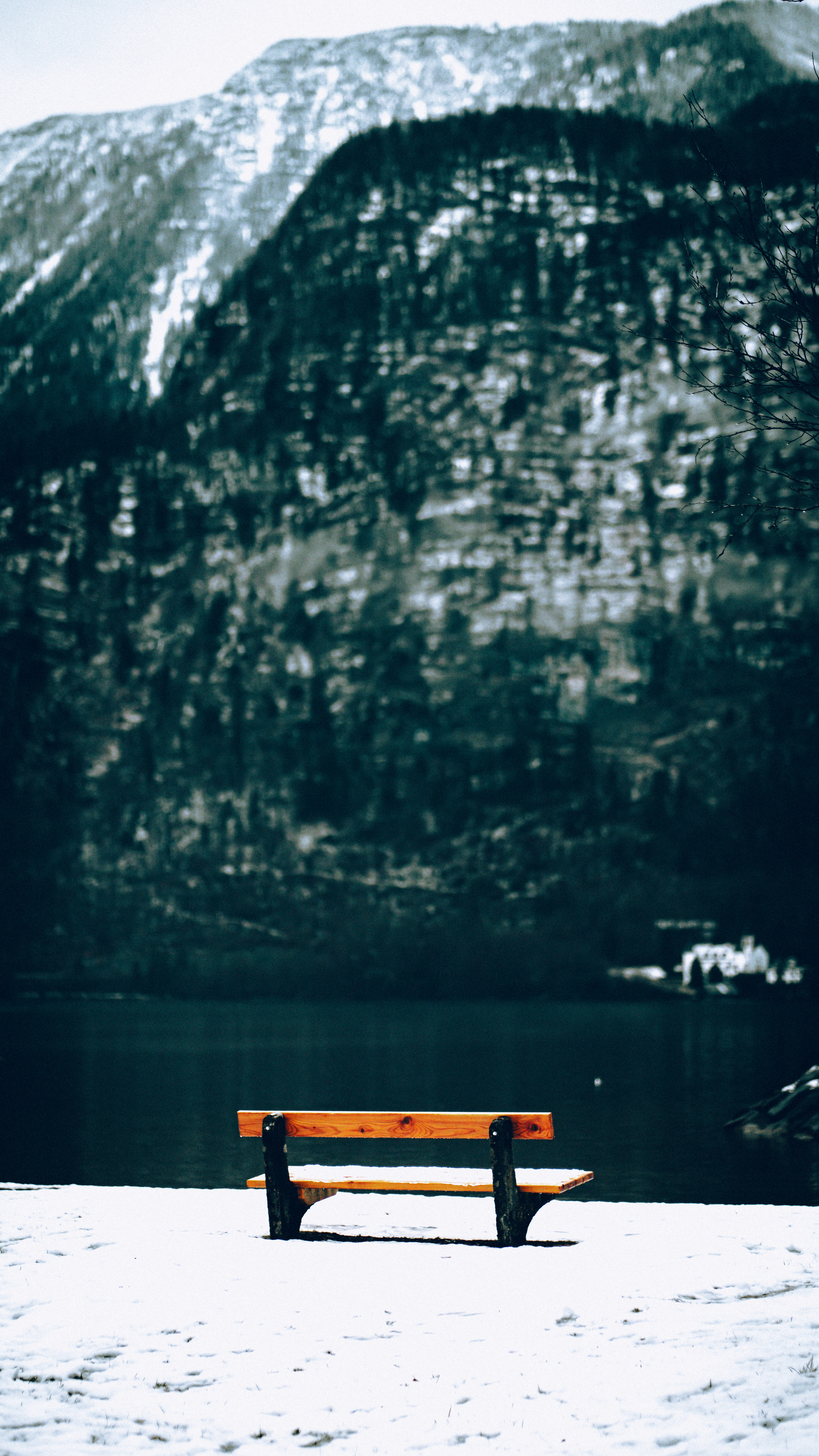 A wooden bench sitting on top of a snow covered ground