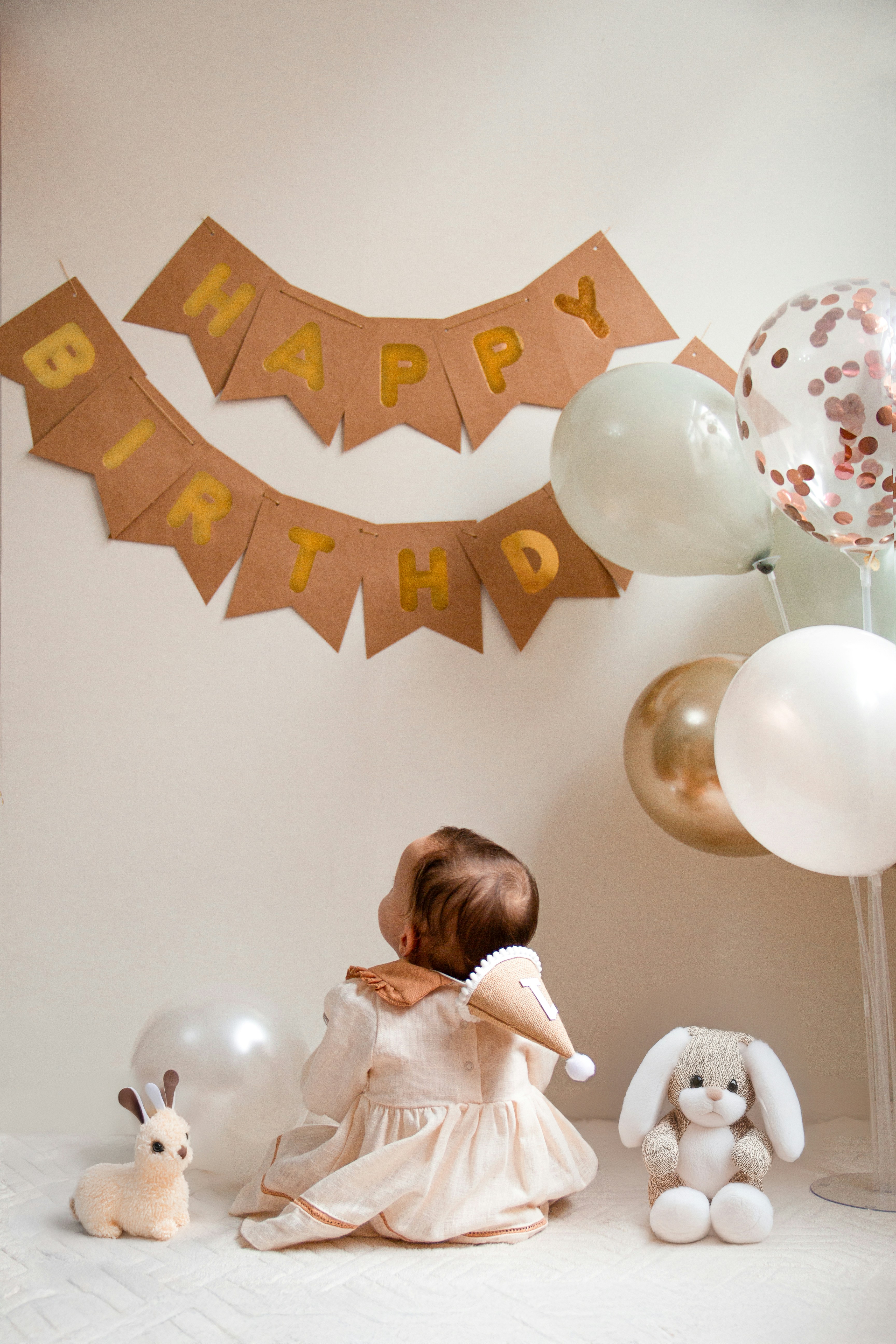 A little girl sitting in front of a birthday banner