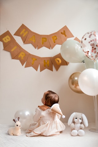 A little girl sitting in front of a birthday banner
