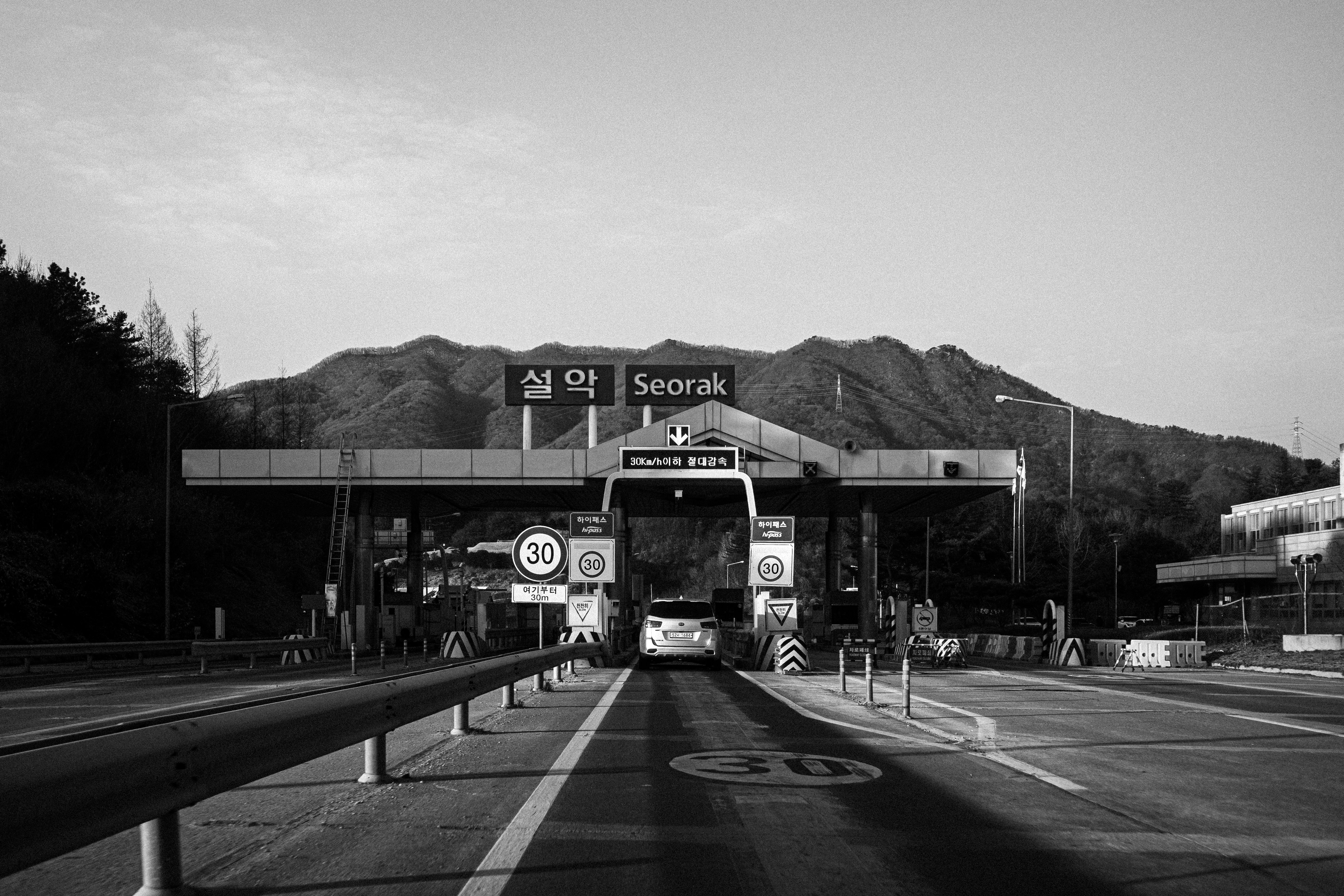 A black and white photo of a highway with mountains in the background