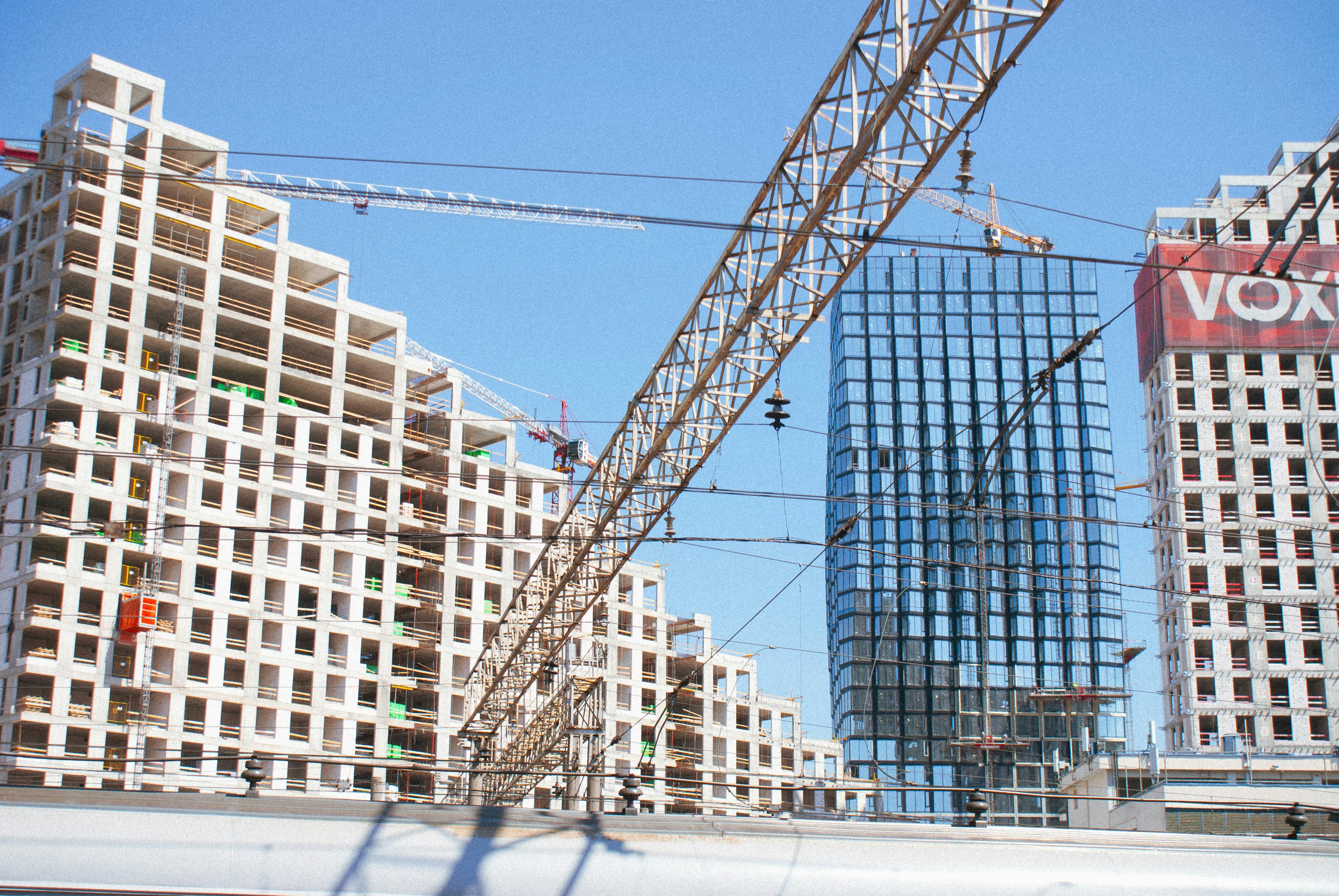 Train traveling past tall buildings under blue sky