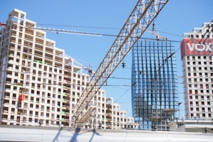 A train traveling past tall buildings under a blue sky