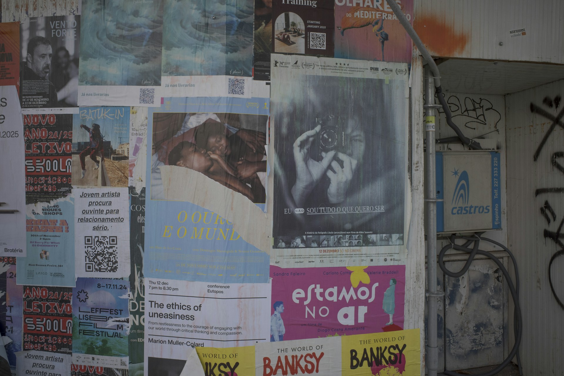 A wall covered in posters and posters next to a building