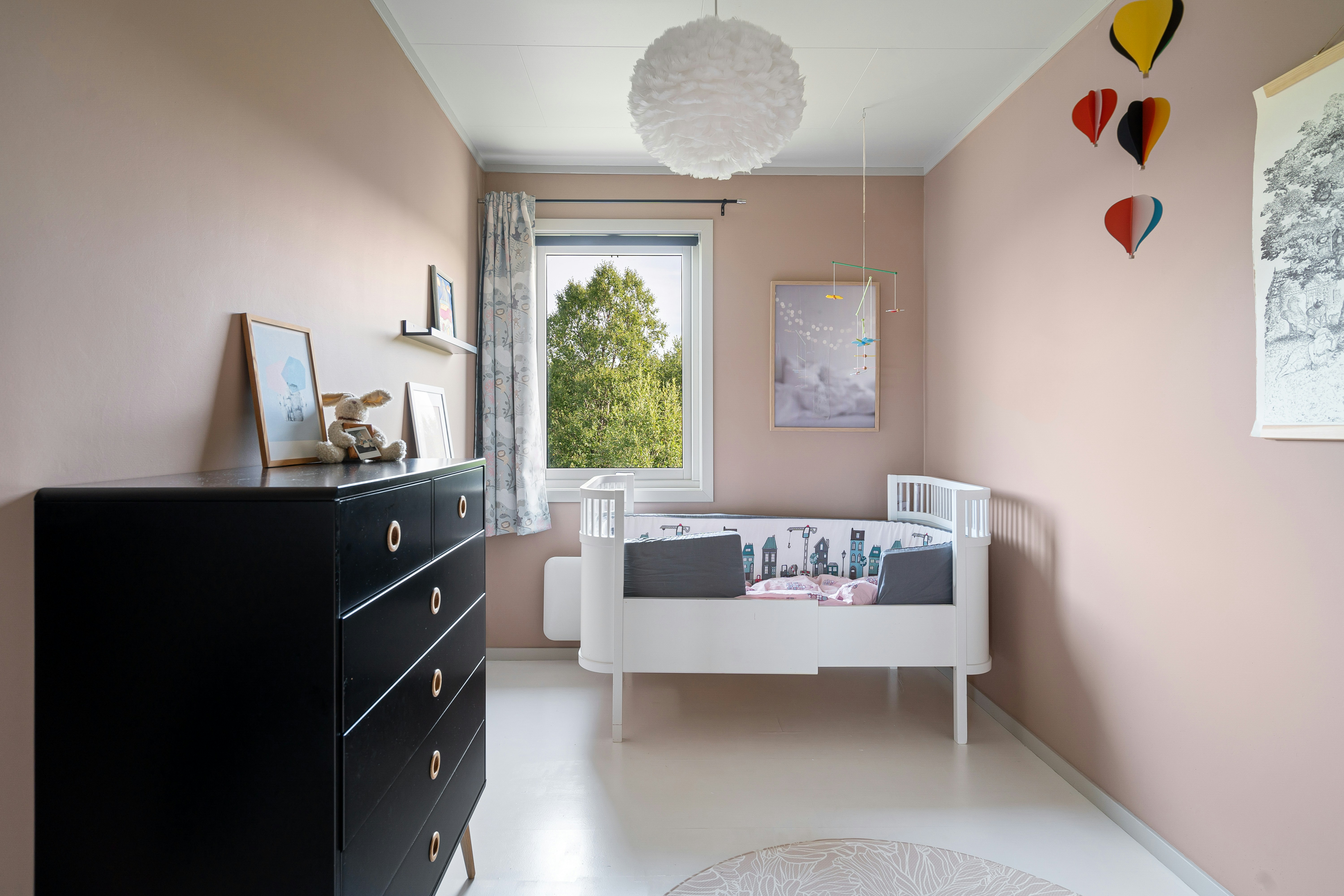 A room with a dresser and a baby crib