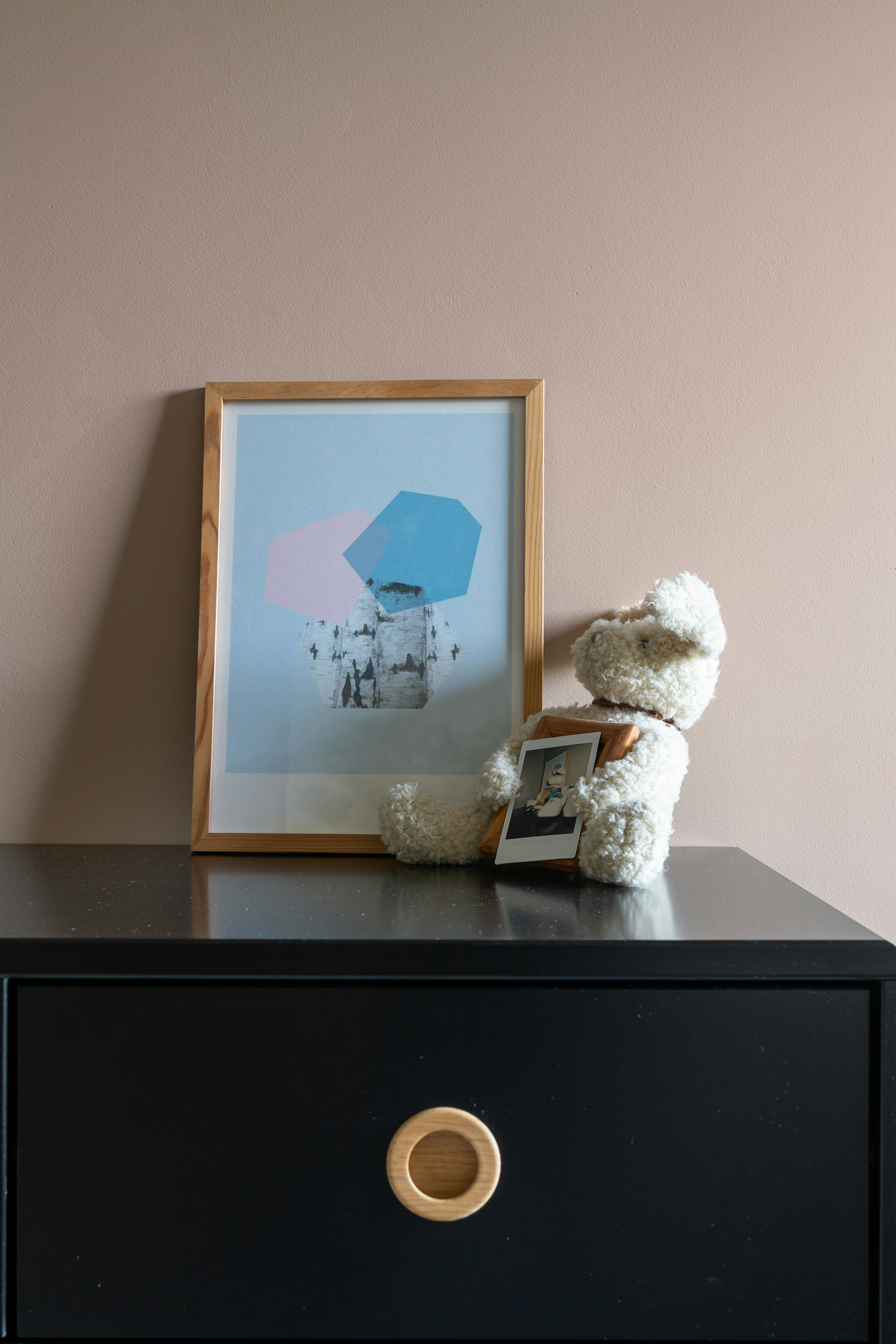 A teddy bear sitting on top of a black dresser