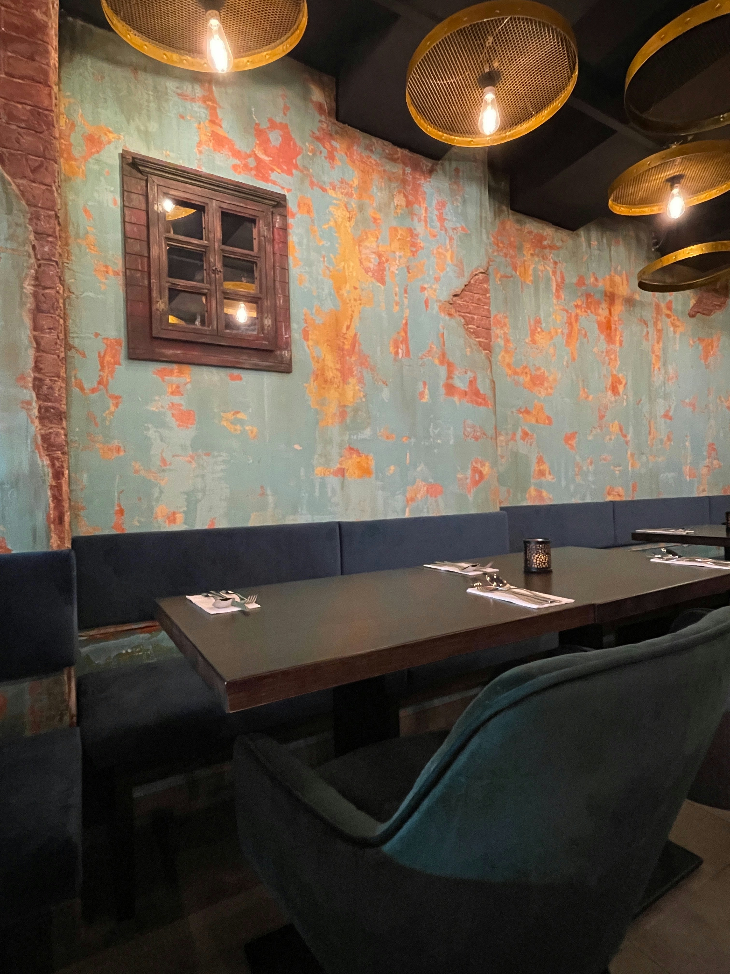 Moody restaurant interior with exposed brick walls, dim pendant lighting, dark wood tables, intimate atmosphere, deep shadows