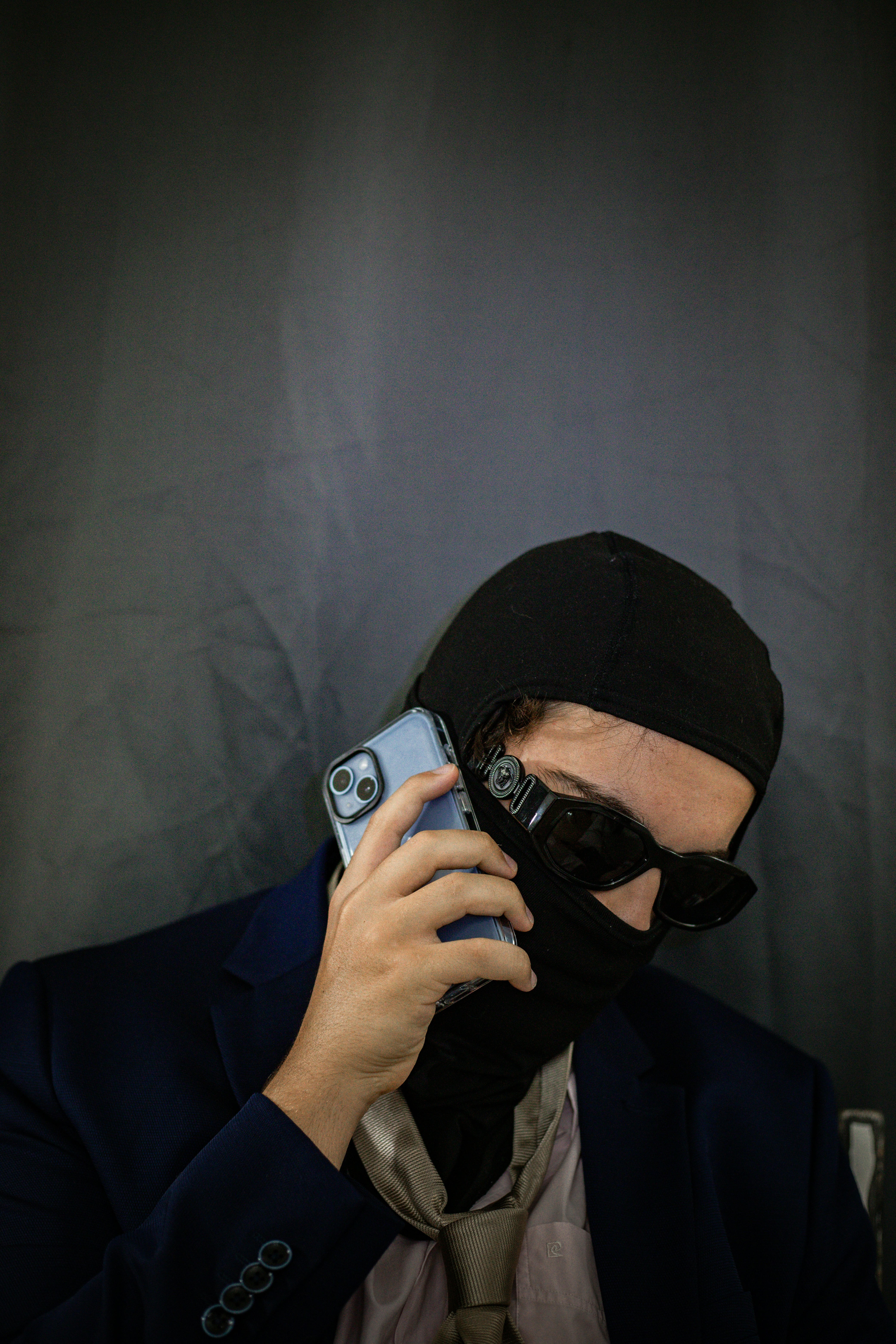 A man wearing a black mask holding a cell phone