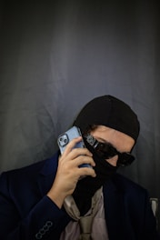 A man wearing a black mask holding a cell phone