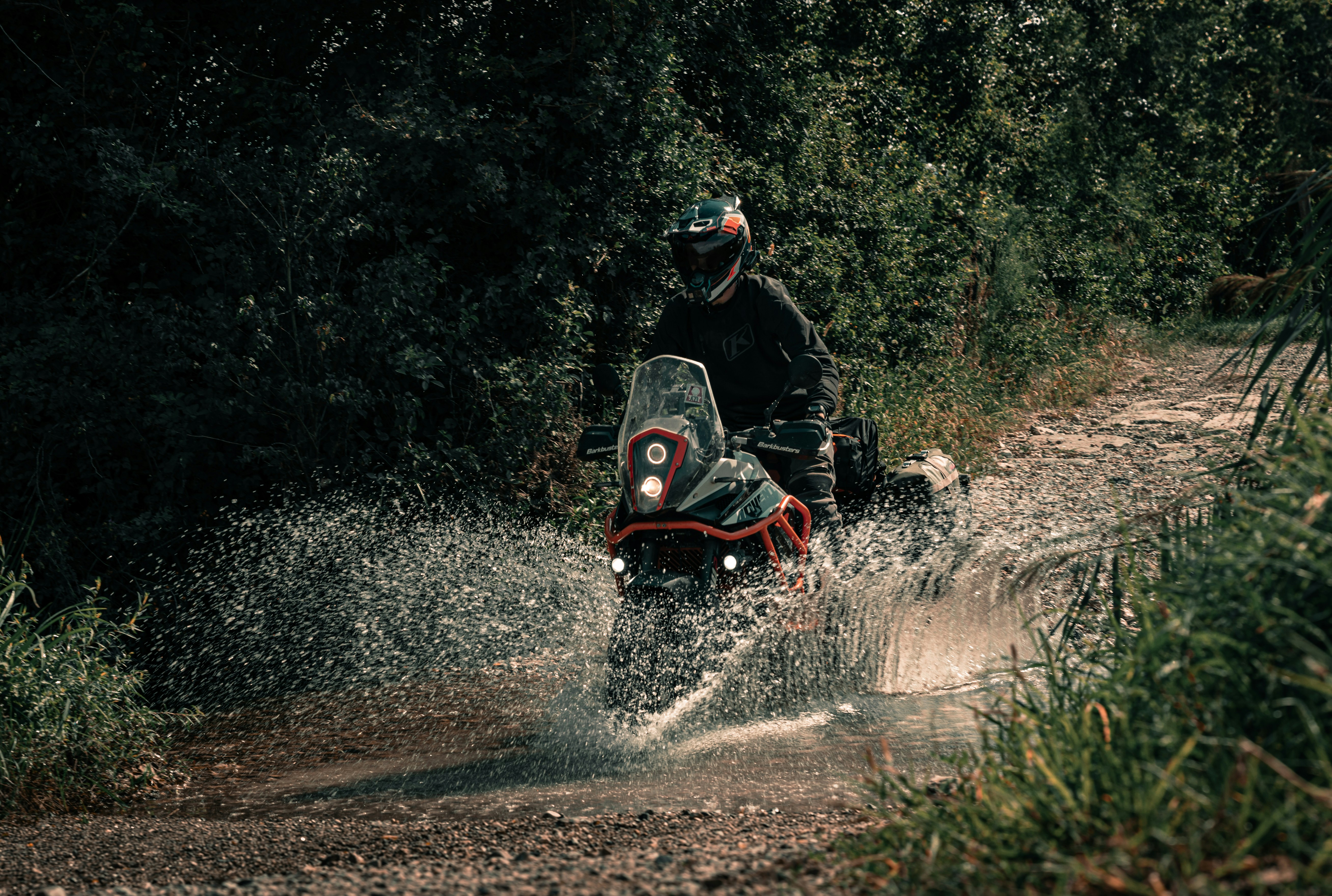 A man riding a motorcycle through a puddle of water