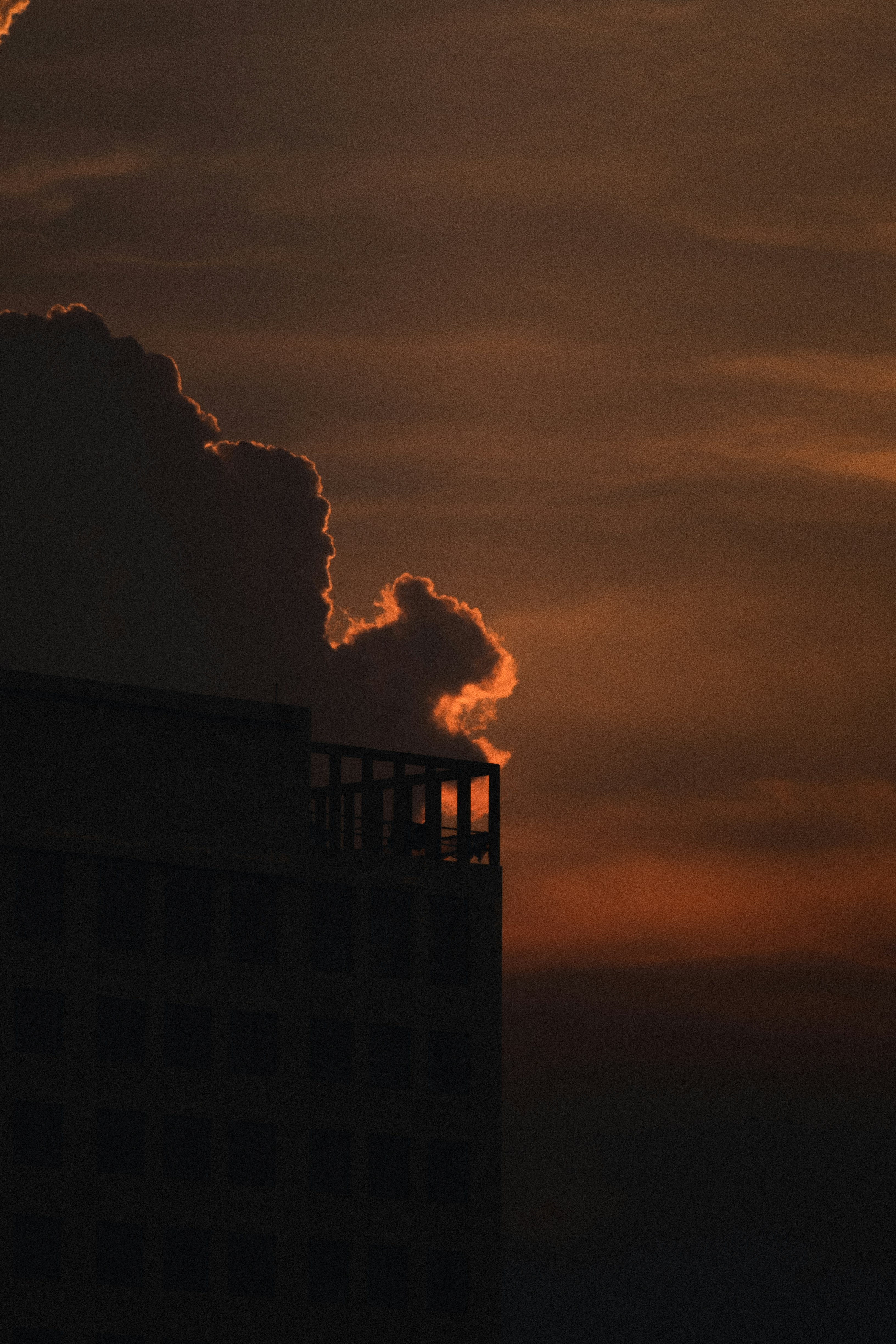 The sun is setting behind a cloud in the sky