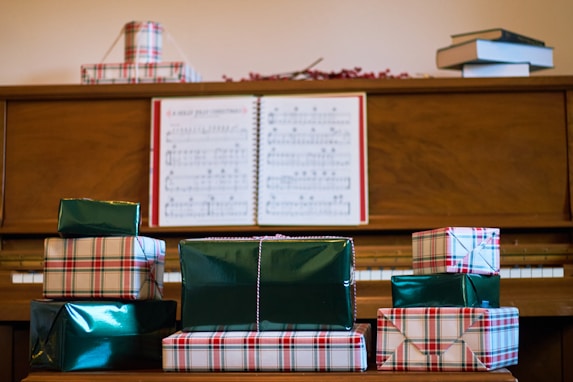 A piano with presents stacked on top of it
