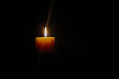 A lit candle in the dark, depicting Grief and Loss, Indicating through the darkness there is light! 