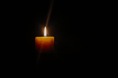 A lit candle in the dark, depicting Grief and Loss, Indicating through the darkness there is light! 