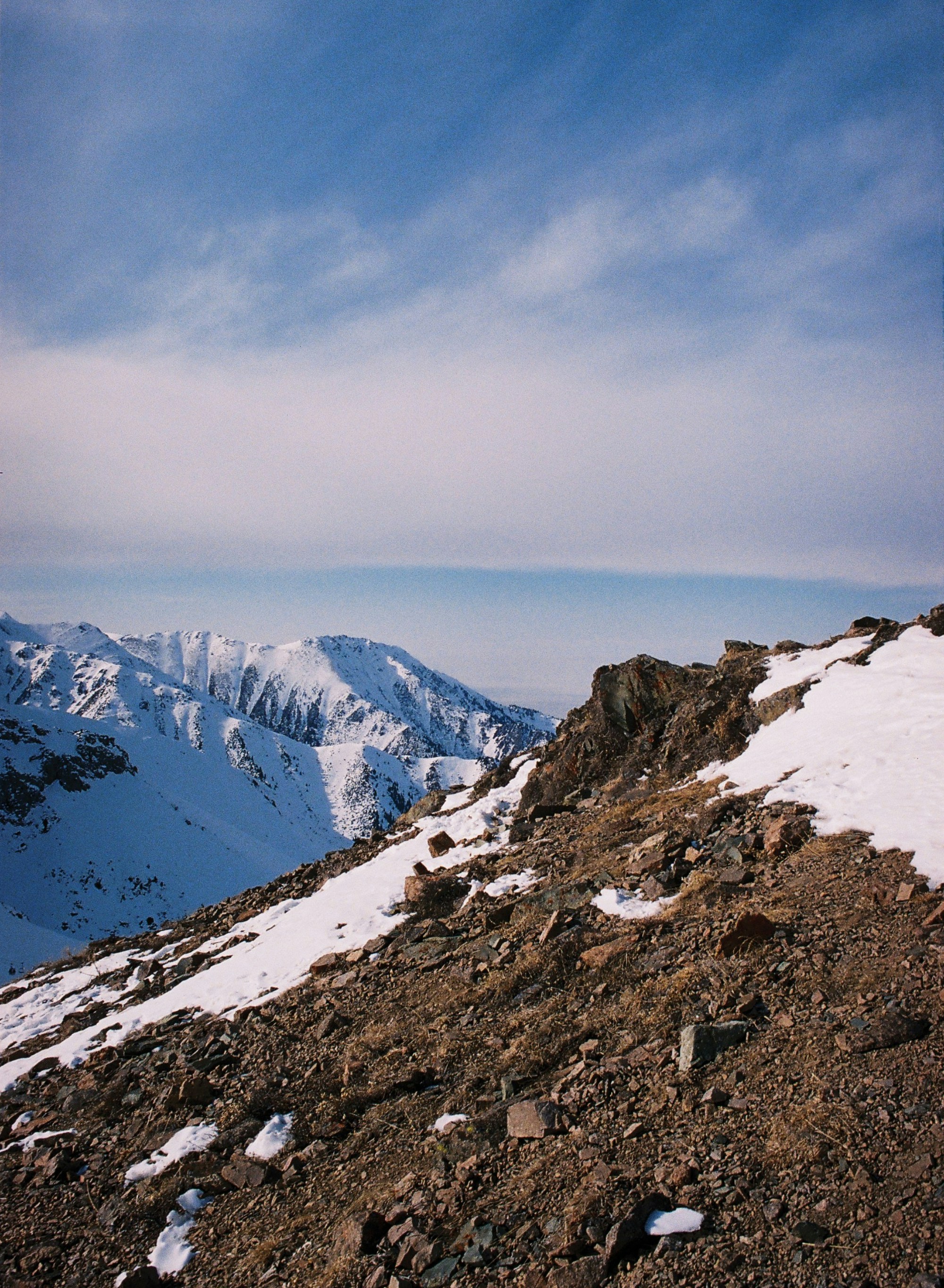 A view of a snowy mountain range from the top of a hill