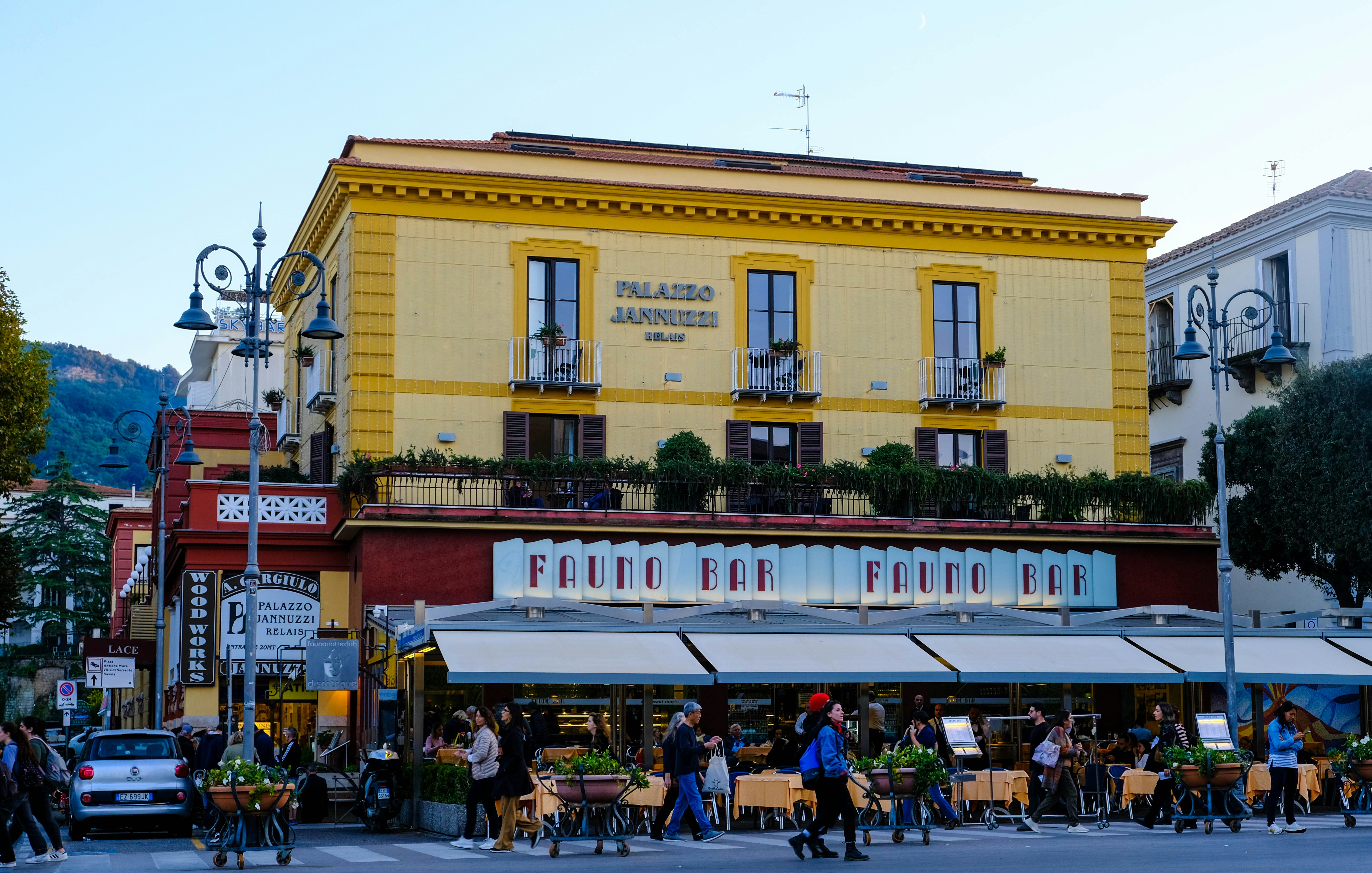 A group of people walking down a street next to a tall yellow building