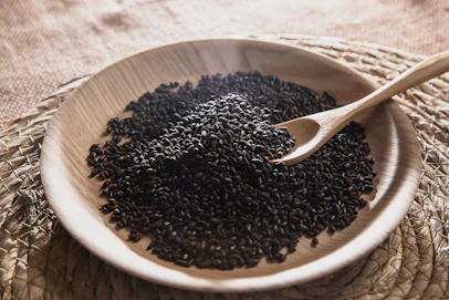 A wooden bowl filled with black seed on top of a table