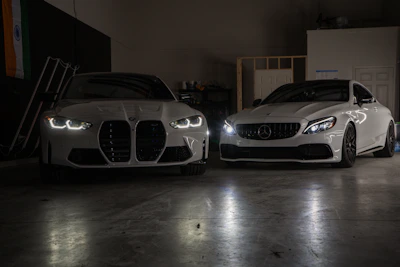 A couple of white cars parked in a garage