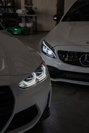 Two white cars parked in a garage next to each other