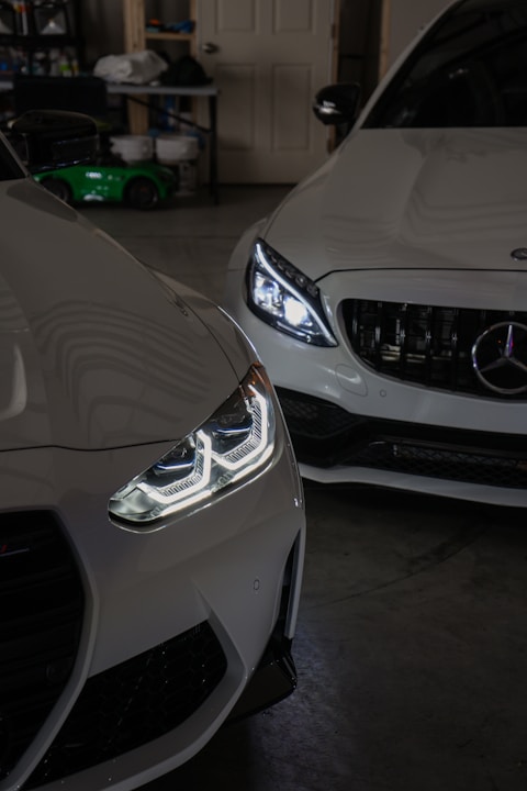 Two white cars parked in a garage next to each other
