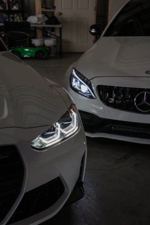 Two white cars parked in a garage next to each other