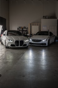 Two white cars parked in a garage next to each other
