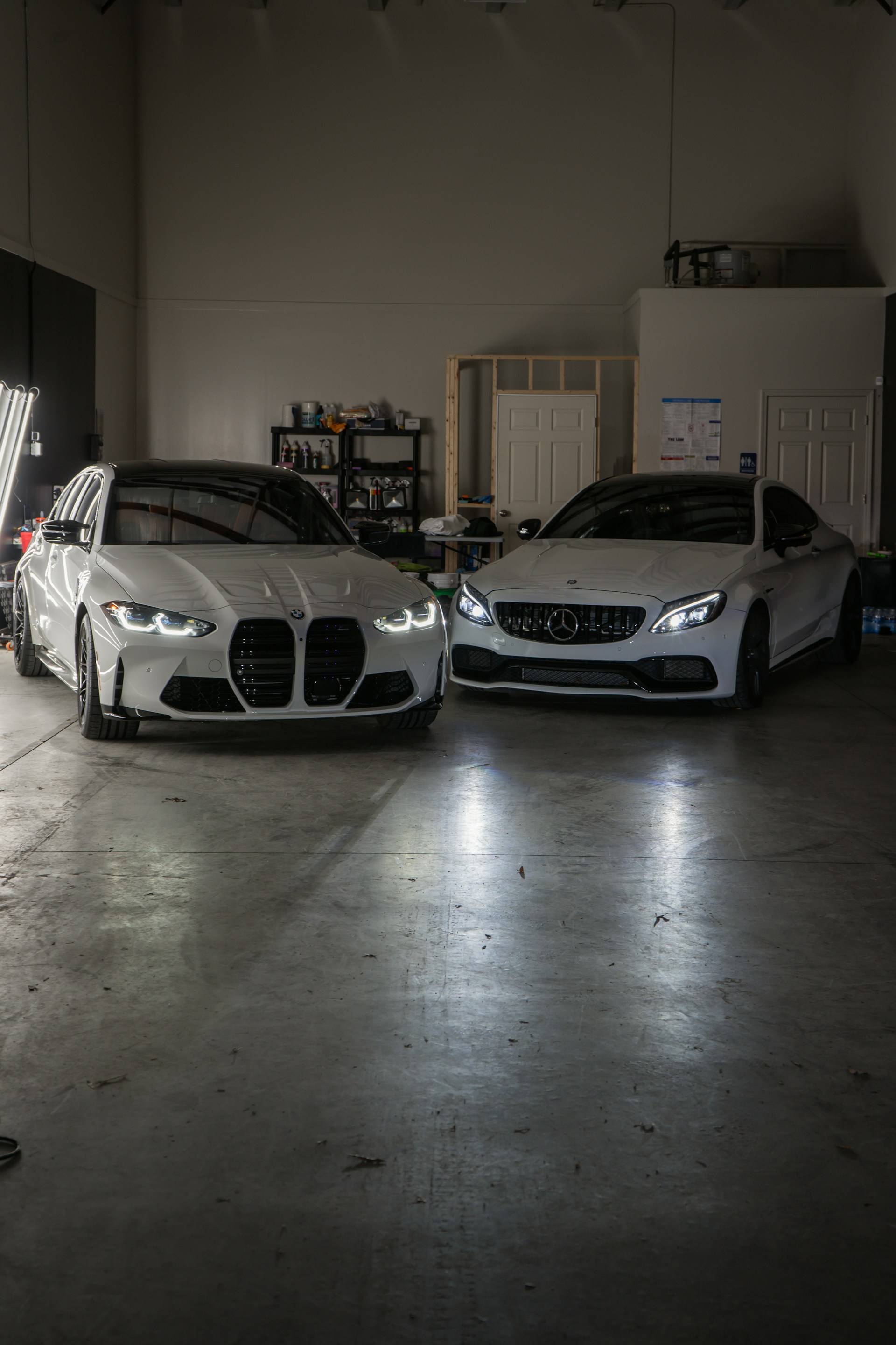 Two white cars parked in a garage next to each other