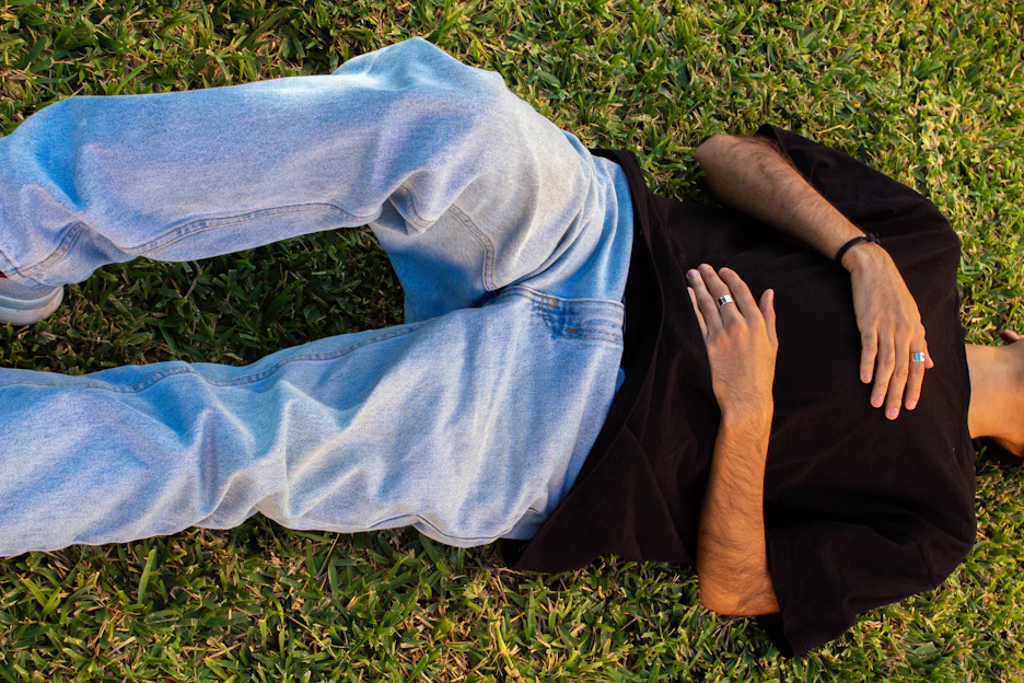 A man laying in the grass with his hands on his chest