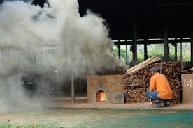 A man kneeling down next to a pile of wood