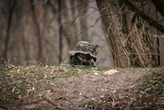 A soldier hiding behind a tree in the woods