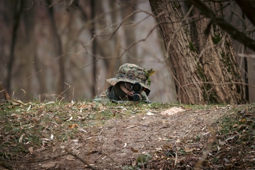 A soldier hiding behind a tree in the woods