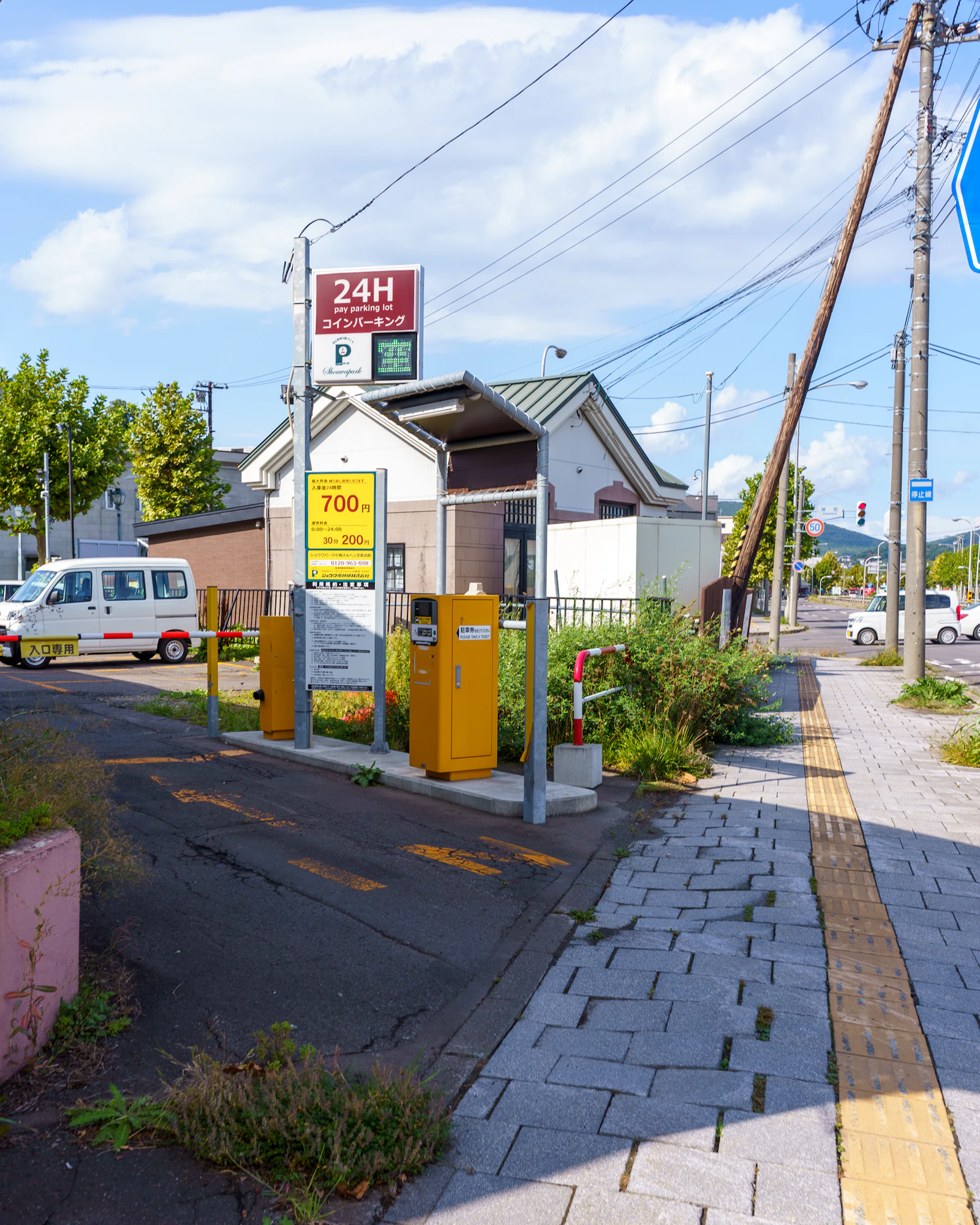 A Japanese stop sign stands beside a road in Otaru