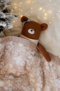 A brown teddy bear laying on top of a blanket