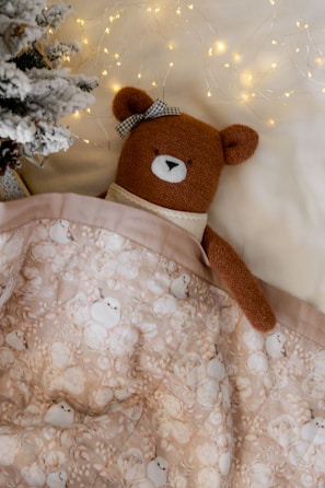 A brown teddy bear laying on top of a blanket