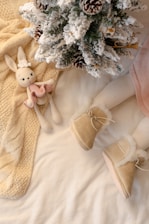 A white bed with a teddy bear and a christmas tree