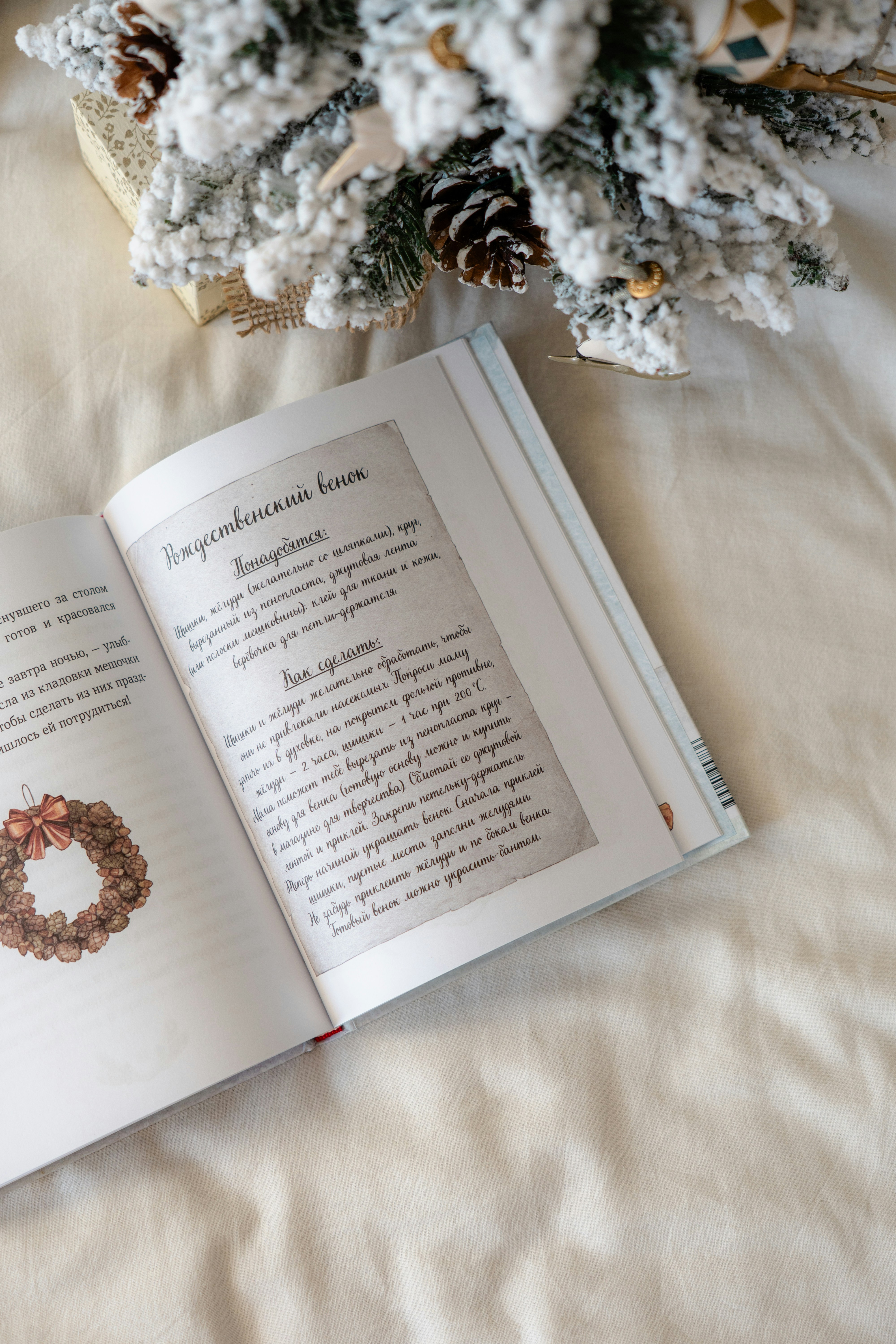 An open book sitting on top of a bed next to a christmas tree