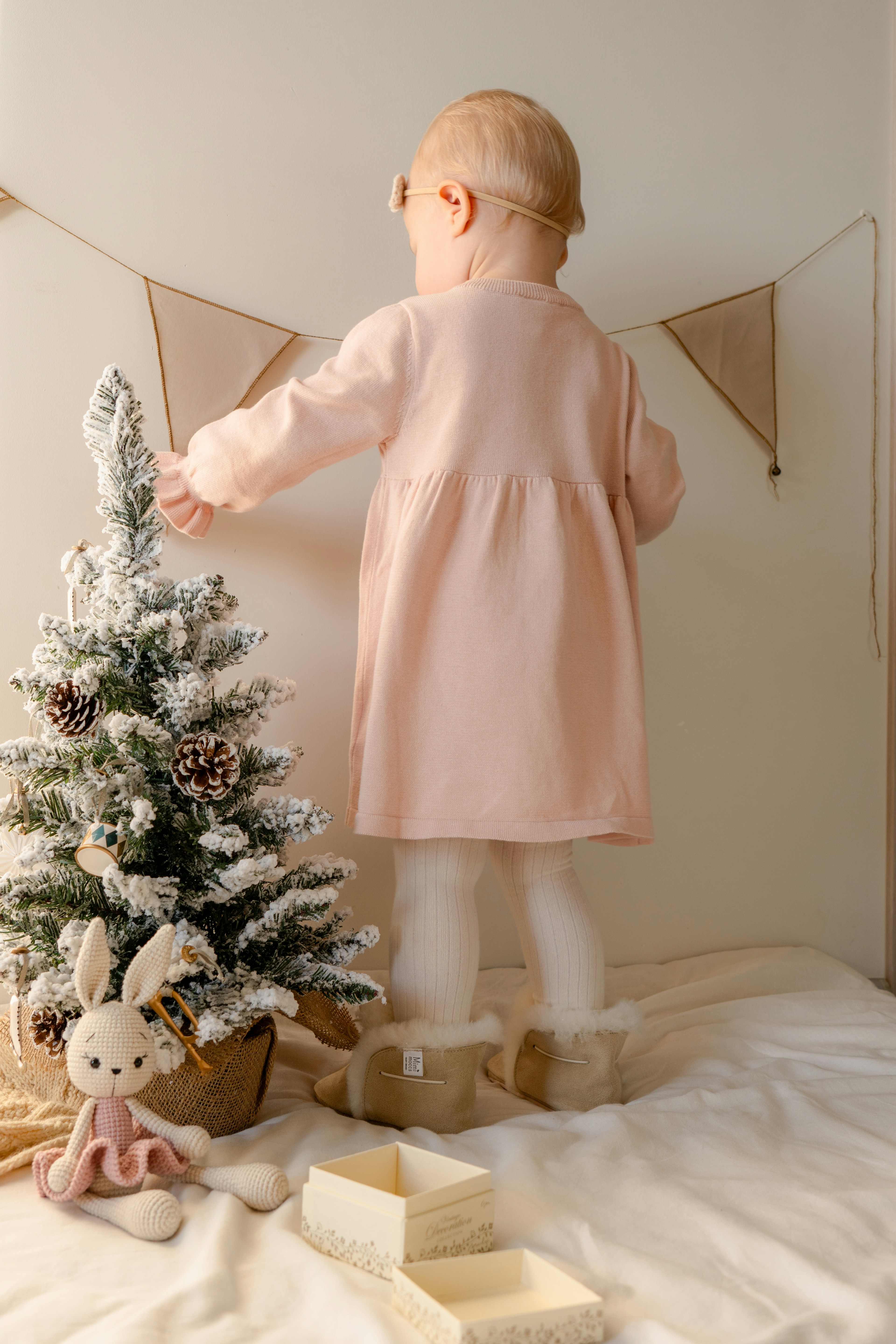 A little girl standing next to a small christmas tree