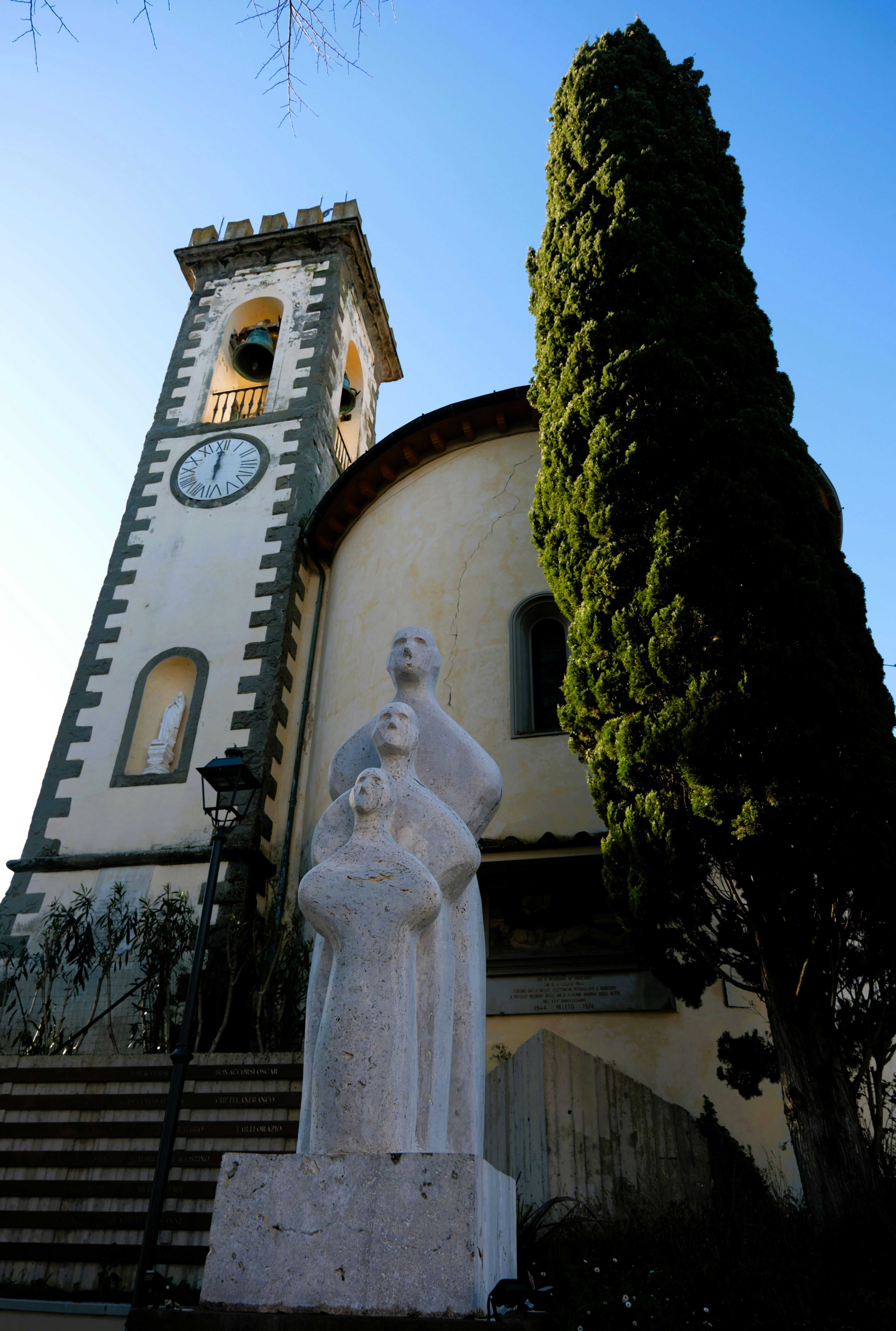 Una statua di una donna davanti a un edificio con una torre dell'orologio