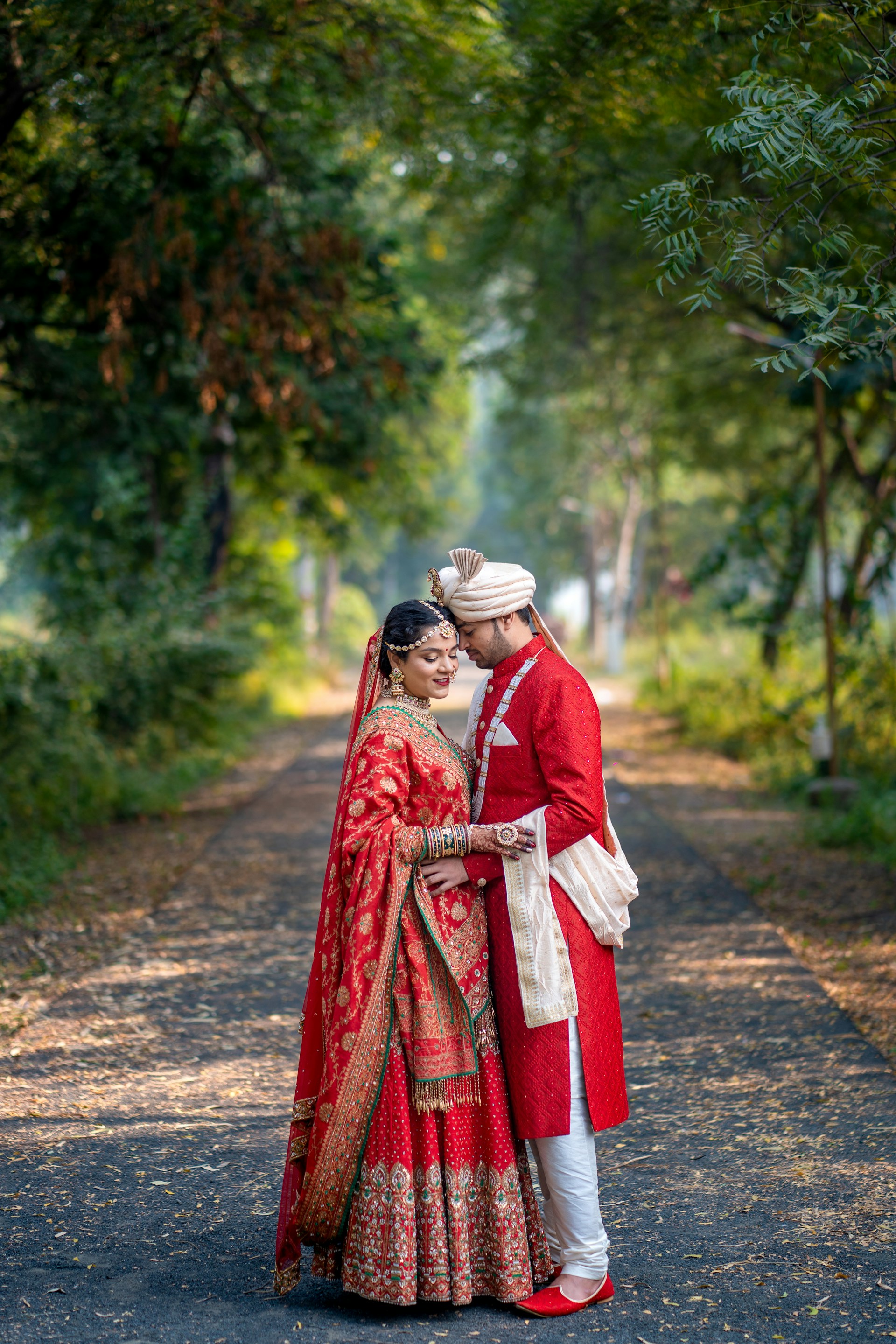 A bride and groom standing on a path in the woods