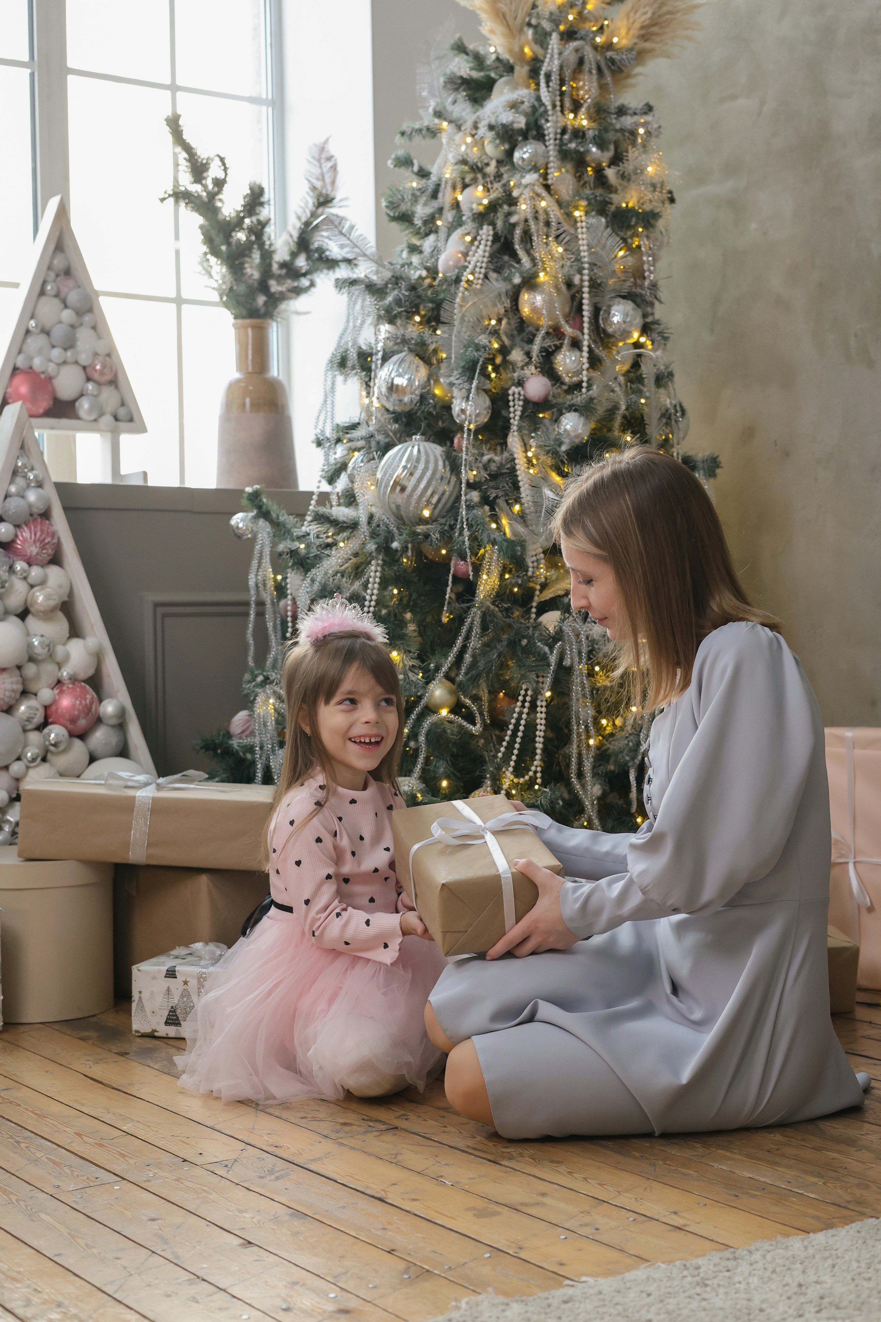 A little girl sitting on the floor next to a christmas tree
