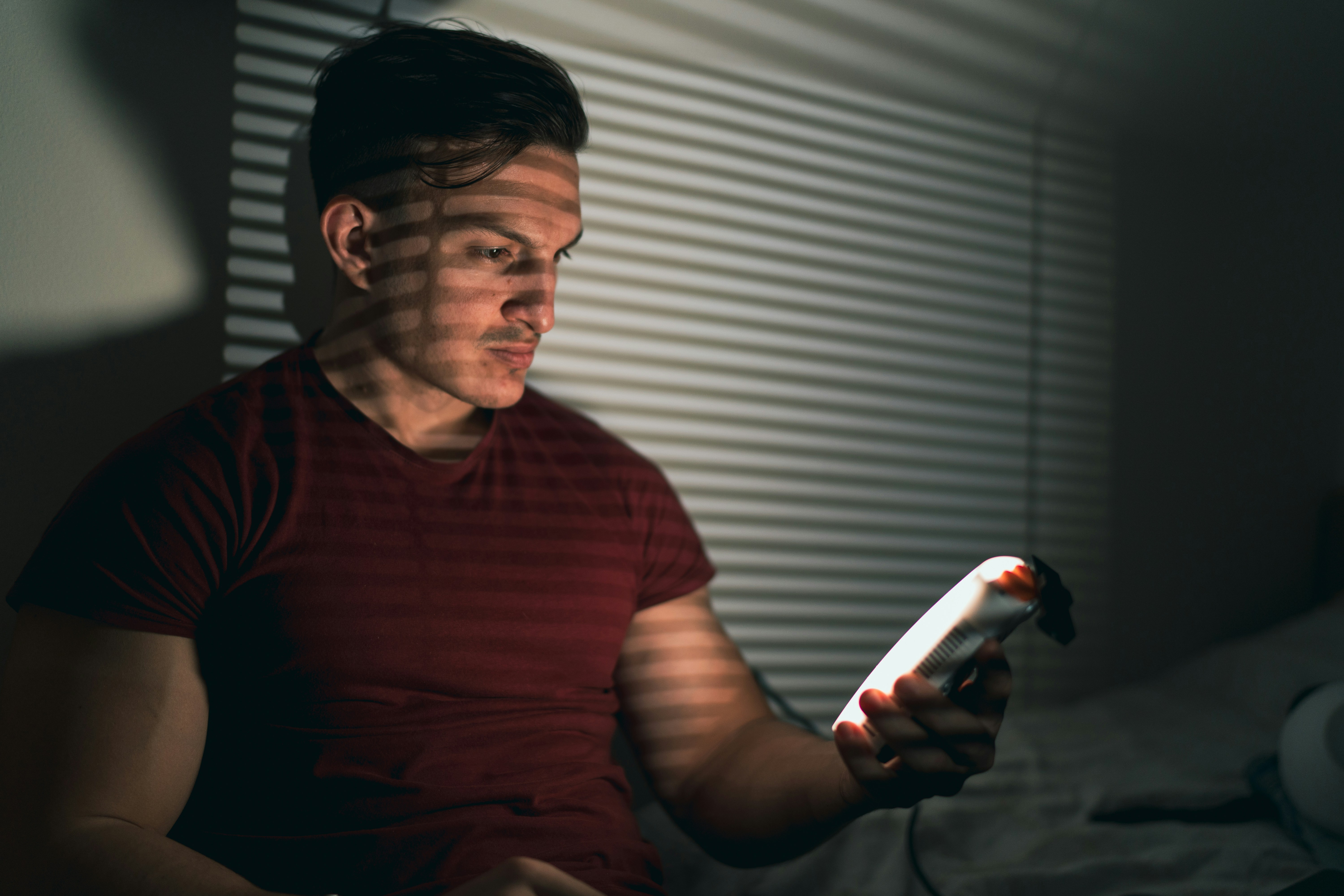 A man sitting on a bed holding a remote control