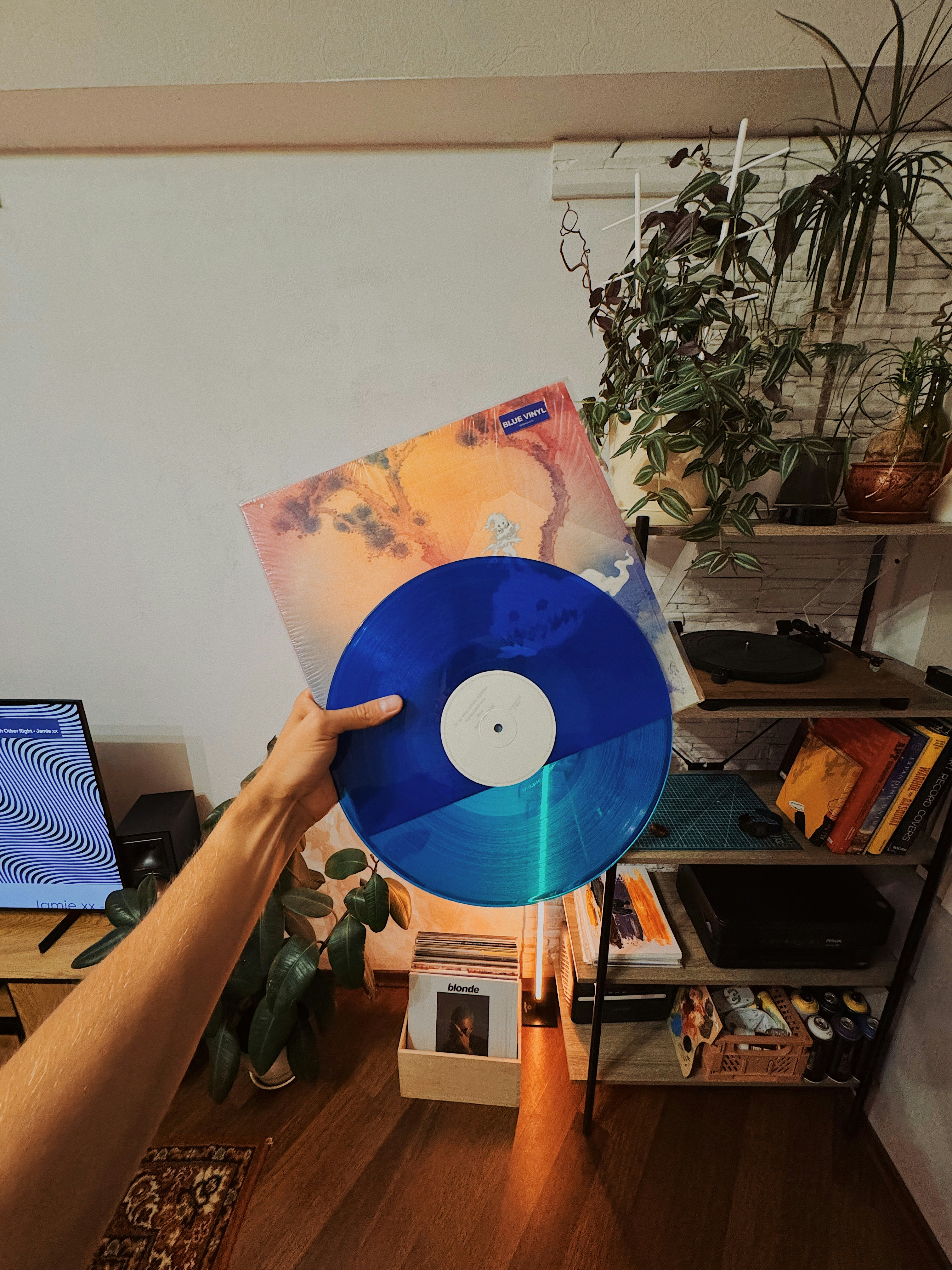 A person holding a blue record in front of a laptop
