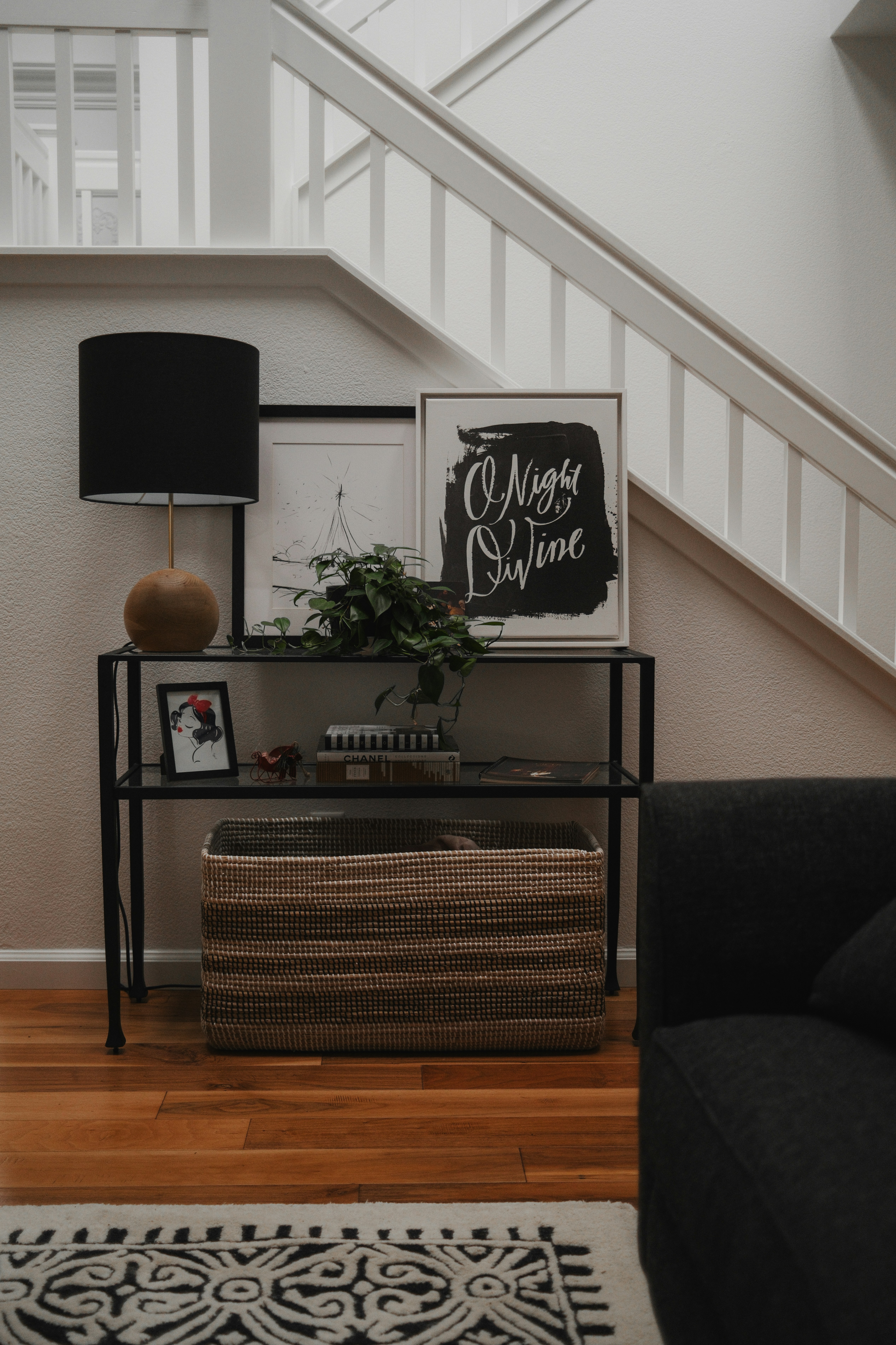A living room with a black couch and a white stair case
